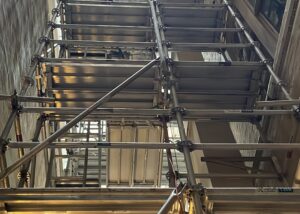 Aluminium scaffolding installed in a narrow laneway between buildings, viewed from ground level.