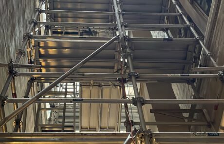 Aluminium scaffolding installed in a narrow laneway between buildings, viewed from ground level.