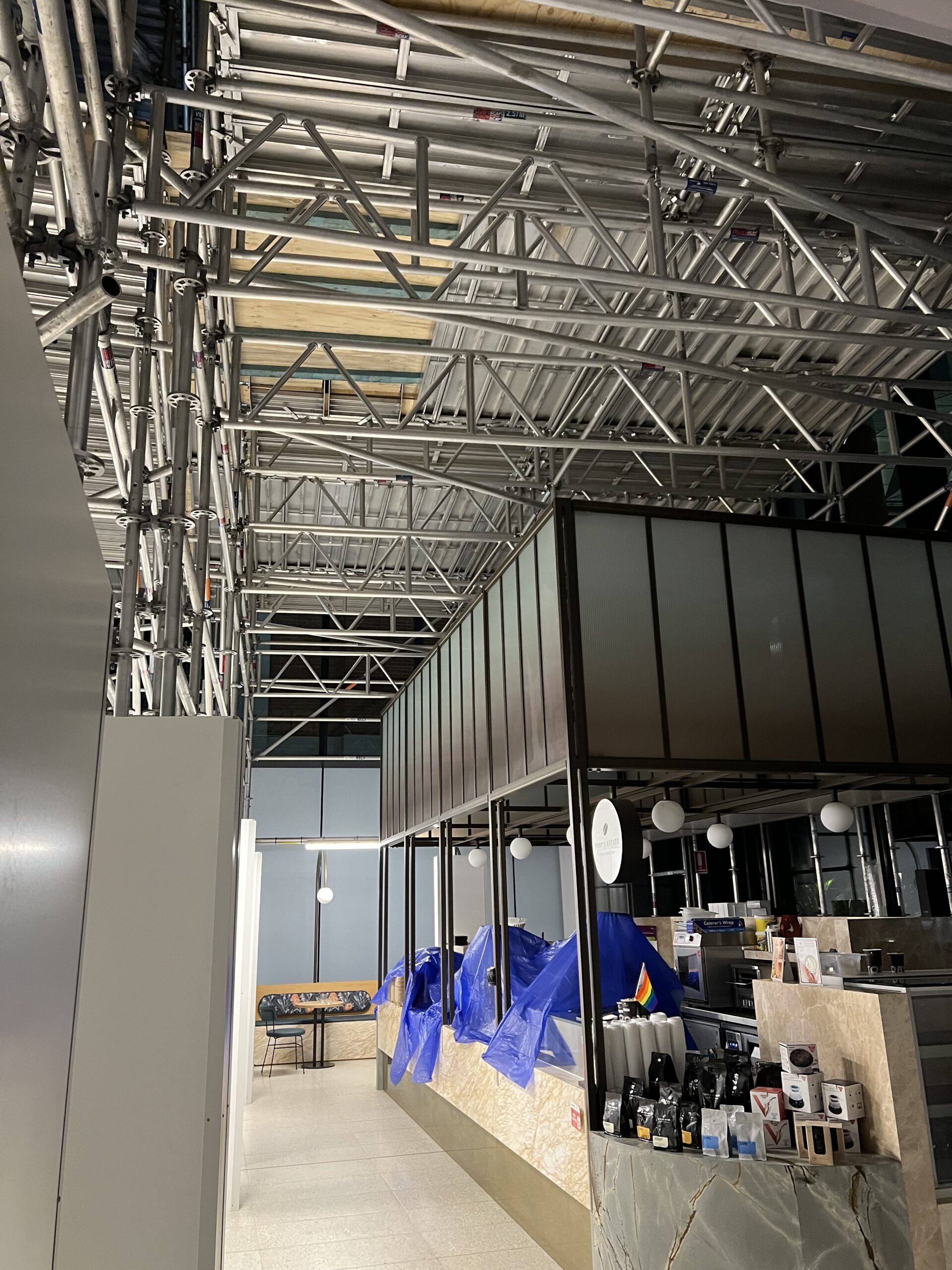 Aluminium_scaffolding_above_a_cafe_Sydney_Scaffolding_Salesforce_building_180_George_St Aluminium scaffold truss and overhead deck installed above a lobby café in the Salesforce Sydney CBD building, allowing ceiling repairs while the café remains open below.