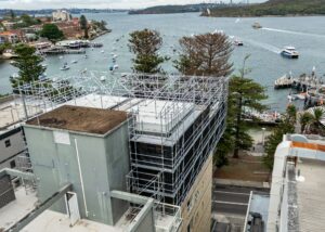 Rooftop cantilevered scaffold on apartment building in Manly with Sydney Harbour in background