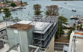 Rooftop cantilevered scaffold on apartment building in Manly with Sydney Harbour in background